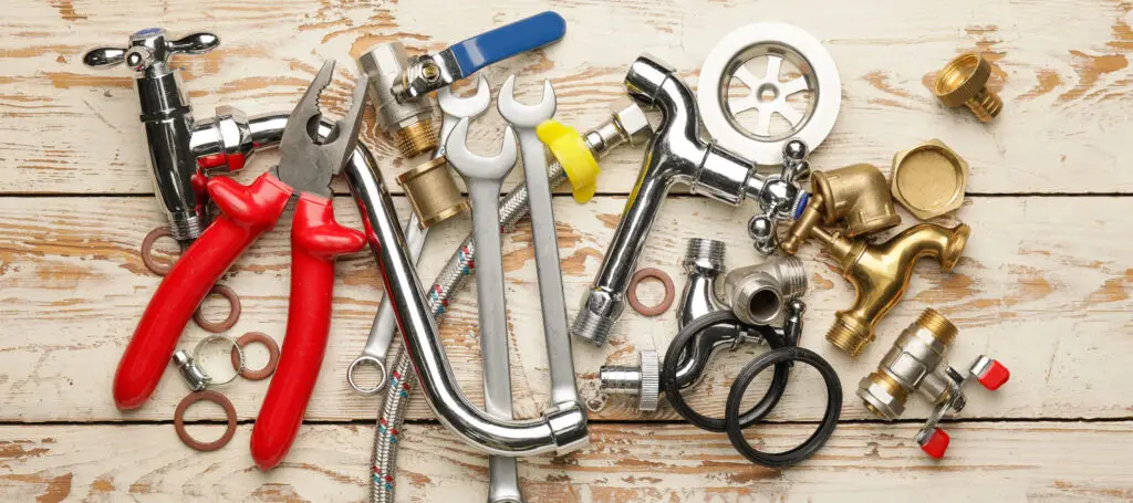 Set of plumber's items on light wooden background, top view