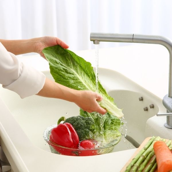 person washing food in sink
