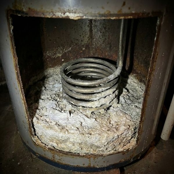 Interior view of a water heater tank filled with sediment buildup caused by hard water minerals.
